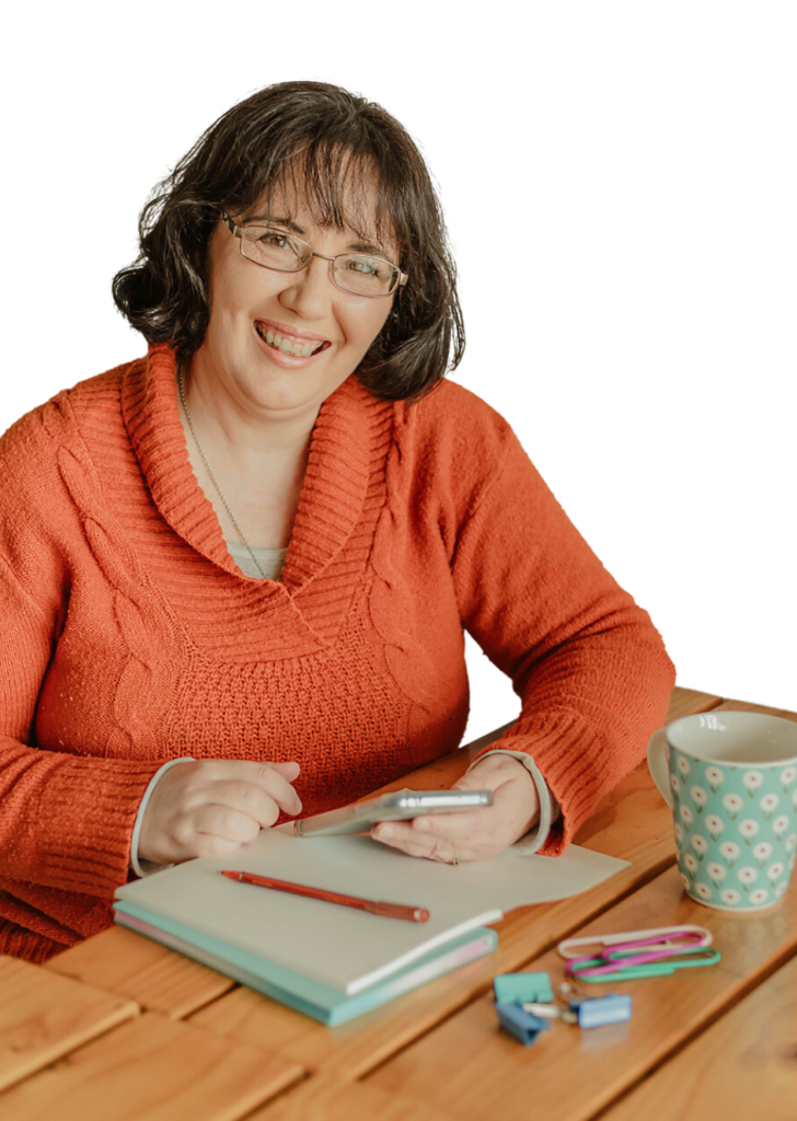 Melanie sitting at a table with her phone and writing books